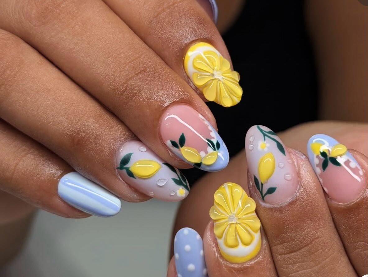 Hand-painted lemon and leaf nail art with pastel blue and white details